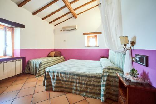 two beds in a room with purple and white walls at Agriturismo Palazzo Bandino - Wine cellar, on reservation restaurant and spa in Chianciano Terme