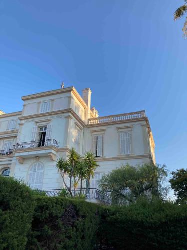 une maison blanche avec un palmier devant dans l'établissement Apartment in a historic villa, à Saint-Raphaël