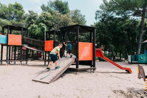 two boys playing on a playground in a park at Camping Park Soline Pitches in Biograd na Moru