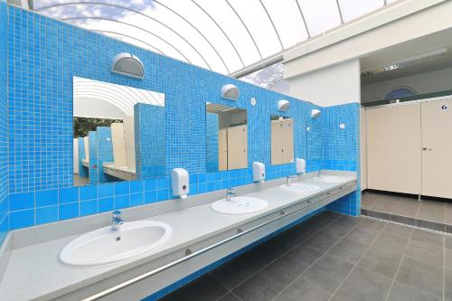a blue tiled bathroom with three sinks and mirrors at Camping Park Soline Pitches in Biograd na Moru