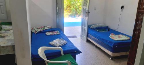 a room with two beds and a chair in it at APARTAMENTO x 4 pessoas no VILLAGE DAIANE TAQUARY Guaibim Valença Bahia in Valença
