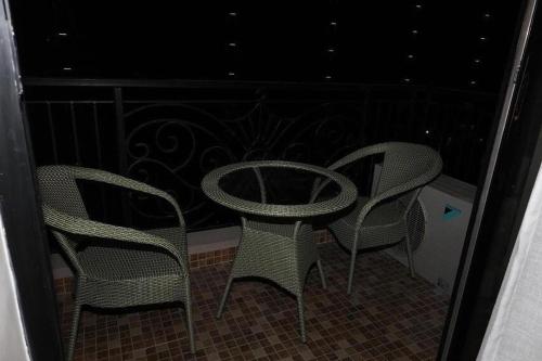 three chairs and a table on a balcony at night at My Guest Stay at Omaxe Hazratganj in Lucknow