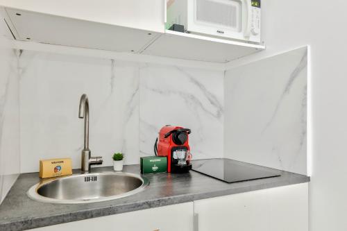 un comptoir de cuisine avec un évier et un micro-ondes dans l'établissement New & Design Studios in the Heart of Le Marais, à Paris