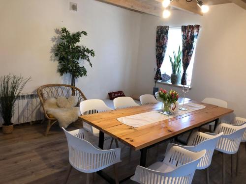 a dining room with a wooden table and white chairs at Agroturystyka Siedlisko in Kowiesy