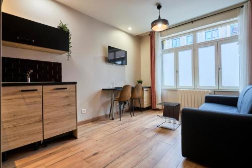un salon avec un canapé et une télévision sur un mur dans l'établissement Vieux Lille Appartement 2 personnes tout équipé, à Lille