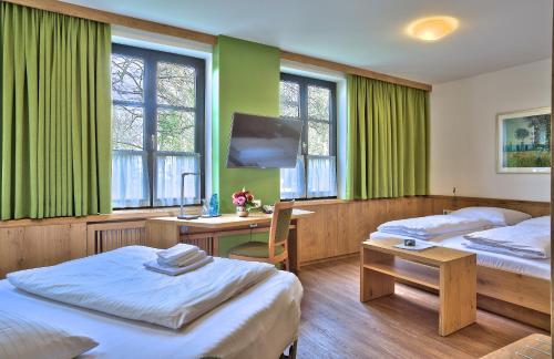 a room with two beds and a desk and a tv at Hotel zur Mühle in Ismaning