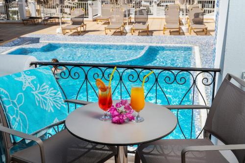 two cocktails on a table on a balcony with a pool at Glaros Hotel Apartment in Agia Galini