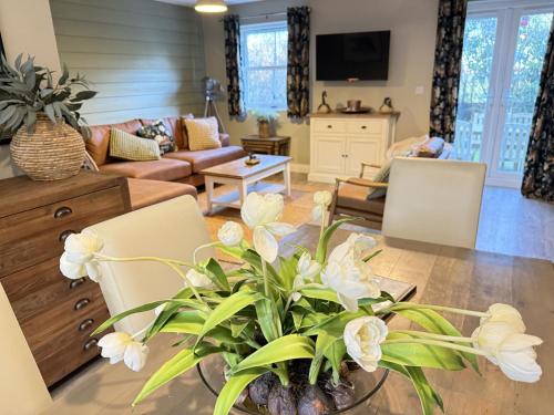 ein Wohnzimmer mit einer Couch und einem Tisch mit Blumen in der Unterkunft Baybreak - Part of the The Bay Filey Holiday Village with pool, gym and direct beach access, pub, restaurant, tennis and meadows walks in Filey