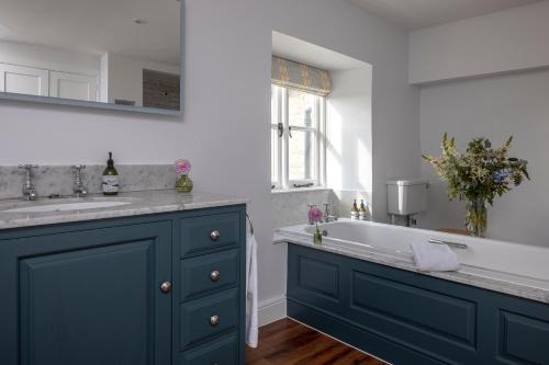 a bathroom with a tub and a sink and a window at Brokenborough Farmhouse in Malmesbury