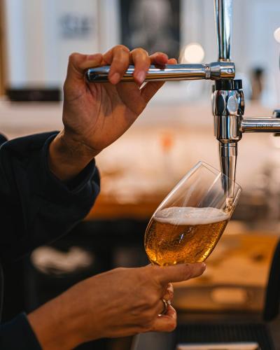 a person is holding a glass of beer at Köpmans Boutique Hotel & Bistro in Höganäs