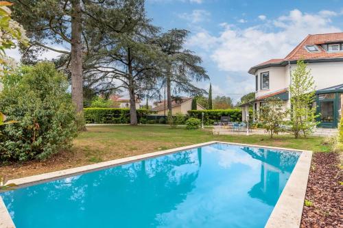 a blue swimming pool in front of a house at Green Place - Amazing house with swimming pool in Caluire-et-Cuire