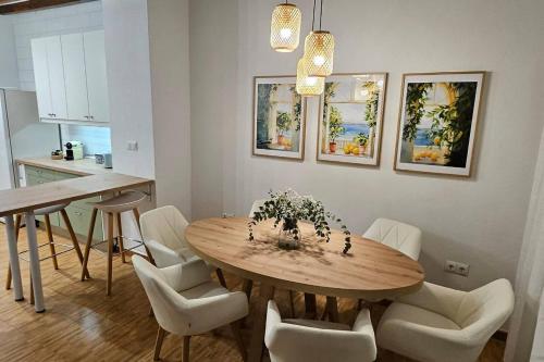 a dining room with a wooden table and white chairs at LovelyLoft Trafalgar in Alicante