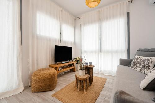 a living room with a couch and a tv at Yara Apt 40m from the Beach Jacuzzi & Rooftop in Agia Anna Naxos