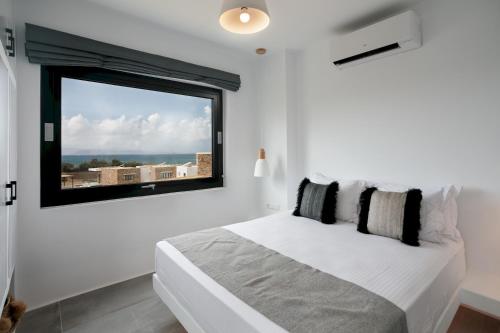 a white bedroom with a large window and a bed at Villa Andalusia in Naxos Chora