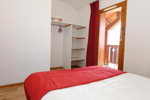 une chambre avec un lit avec une couverture rouge dessus dans l'établissement Charmant chalet de montagne en bord de piste, à Valmeinier