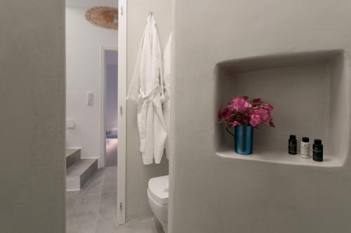 a bathroom with a toilet and a vase of flowers on a shelf at Villa Andalusia in Naxos Chora