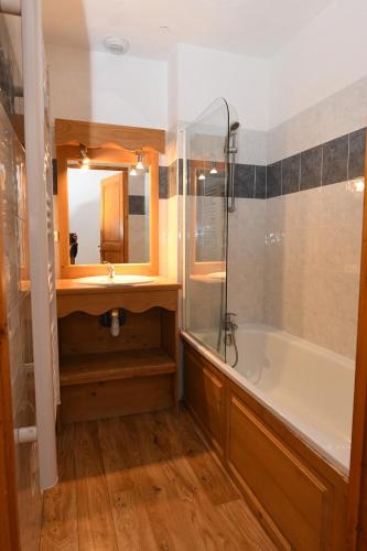 une salle de bain avec un lavabo, une baignoire et un miroir dans l'établissement Charmant chalet de montagne en bord de piste, à Valmeinier