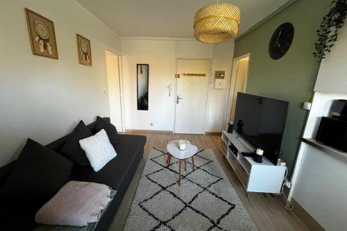 un salon avec un canapé noir et une télévision dans l'établissement SOH Rent Strasbourg appartement wifi terrasse, à Strasbourg