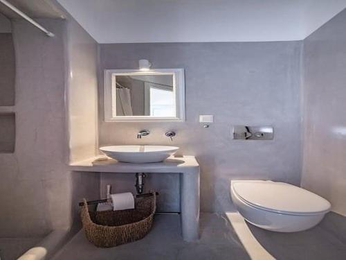 Un baño con lavabo, inodoro y espejo. en Magnifica, en Naxos Chora