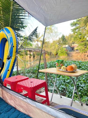 a table and chair in a boat with a table and a table at HOMESTAY Hoàng GIa in Ấp Ông Tú