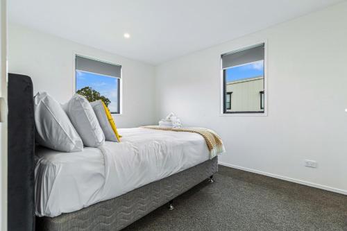 a white bedroom with a large bed with two windows at Auckland airport homes six minutes from airport three bedrooms two and half bathrooms in Auckland