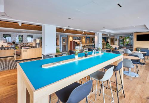 a large blue table in a restaurant with chairs at B&B HOTEL Deauville-Touques in Deauville