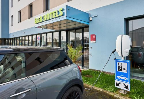 a car plugged into a parking meter in front of a building at B&B HOTEL Deauville-Touques in Deauville
