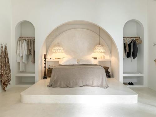 a white bedroom with a bed with an arched ceiling at Poem House Bali in Munggu