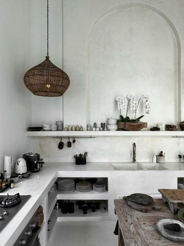a white kitchen with a sink and a table at Poem House Bali in Munggu