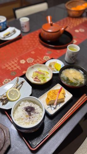 a table with plates and bowls of food on it at Grandma's island Home Hakata - Matsusaki inn 島のおばあちゃんち宿伯方 - 松崎旅館 in Hakata-jima