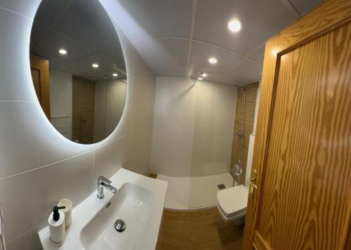 a bathroom with a sink and a mirror and a toilet at Apartament Claudia II in Puerto de Mazarrón
