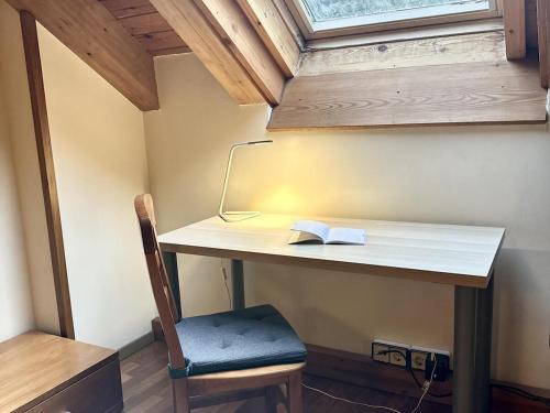 a desk with a book and a lamp and a chair at Mufló, acogedor apartamento en la Molina in Alp