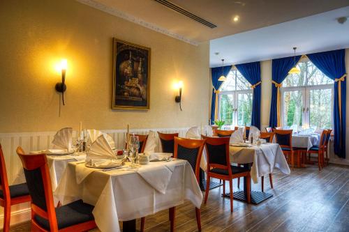 a restaurant with tables and chairs with white tablecloths at KurparkHotel Warnemünde in Warnemünde