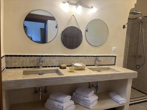 a bathroom with a sink and two mirrors and towels at Riad Hanael Garden & Spa in Fès