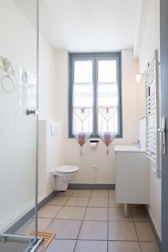 La salle de bains est pourvue de toilettes, d'un lavabo et de 2 fenêtres. dans l'établissement Appartement Moderne, à Honfleur