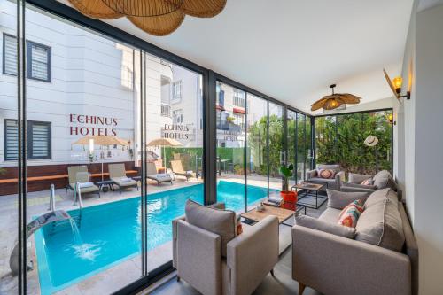 a living room with a swimming pool and windows at Echinus Lara Hotel in Antalya