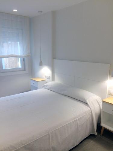 a bedroom with a white bed and two night stands at Apartamentos Angelito Playa América B in Nigrán