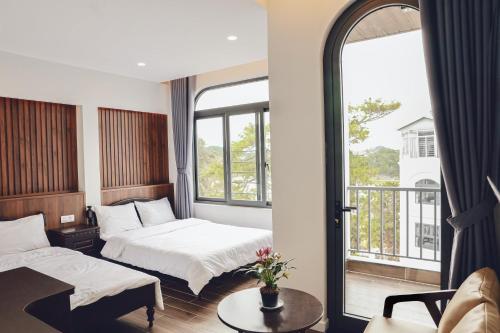 a hotel room with two beds and a balcony at Vĩnh Tuấn Hotel in Da Lat