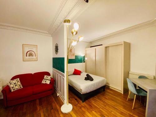Cette petite chambre comprend un lit et un canapé rouge. dans l'établissement Appartement Cambronne Jardin Privatif, à Paris