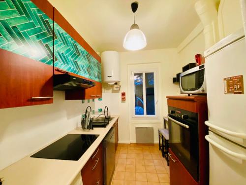 une cuisine avec un évier et un micro-ondes dans l'établissement Appartement Cambronne Jardin Privatif, à Paris