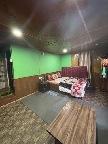a bedroom with a bed and a green wall at Odyssey Stays Rimbi in Pelling