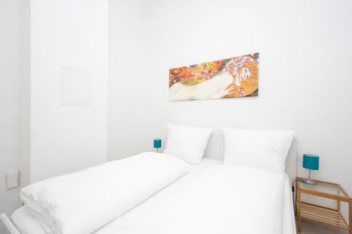 Apartment Uthman Berlin-Neukölln في برلين: غرفة نوم بيضاء بسريرين ولوحة على الحائط
