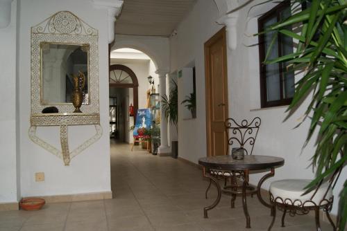a hallway with a table and chairs and a mirror at Hostal Fenix in Jerez de la Frontera