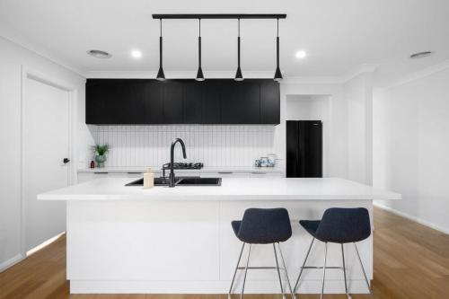 a kitchen with a white counter and two blue bar stools at Albury Oasis in Thurgoona