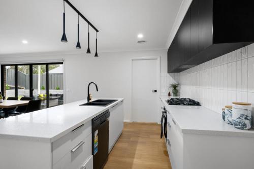 a white kitchen with a sink and a stove at Albury Oasis in Thurgoona