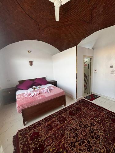 a bedroom with a bed with pink sheets and a rug at Nile View Guest House in Aswan