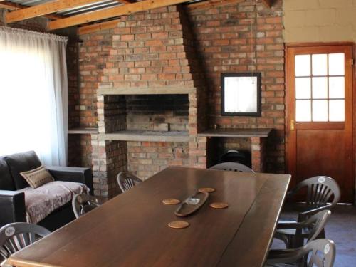 a wooden table in a room with a brick fireplace at Mosamane Guest Farm in Rosendal