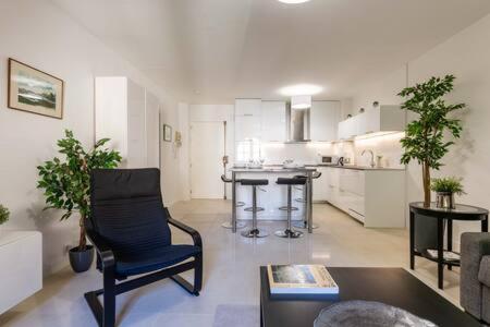 un salon avec une chaise noire et une cuisine dans l'établissement Le Jardinet de la Cathédrale, à Aix-en-Provence