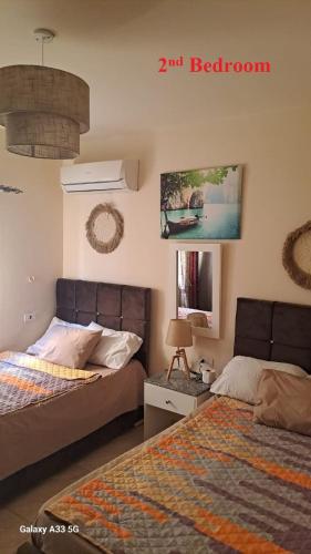 a bedroom with two beds and a tv on the wall at Luxury Chalet in Mountain View 2 , El-Sokhna with Sea View , Pool View and Garden View Families Only in Ain Sokhna