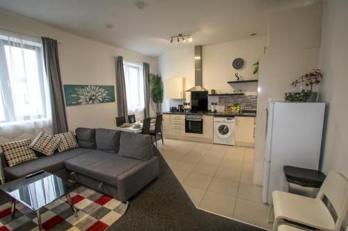 a living room with a couch and a kitchen at Ideal for groups - 2 Bedroom Apartment - Free Parking, Transit links, Close to Stadiums in Manchester